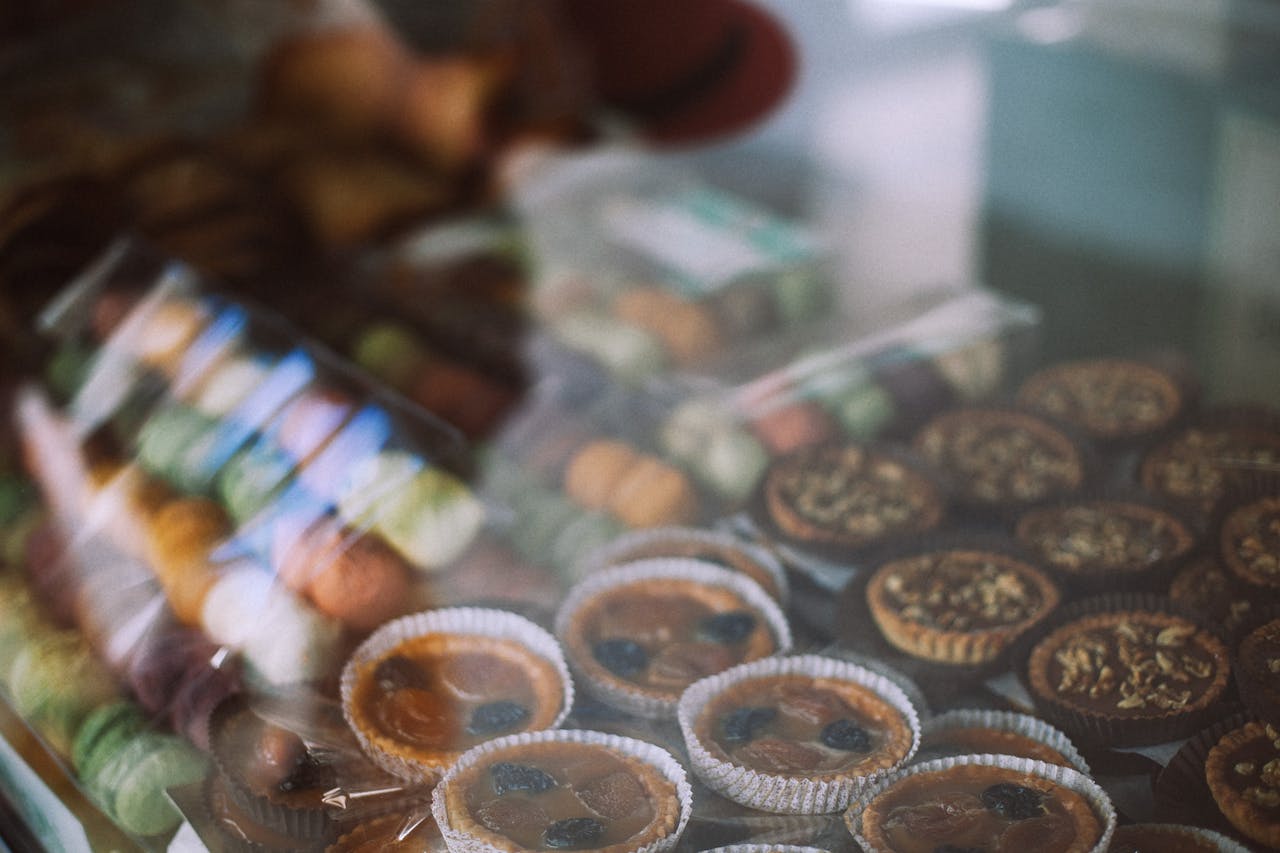 Through glass view of different tasty tartlets and macaroons for sale in sweet shop